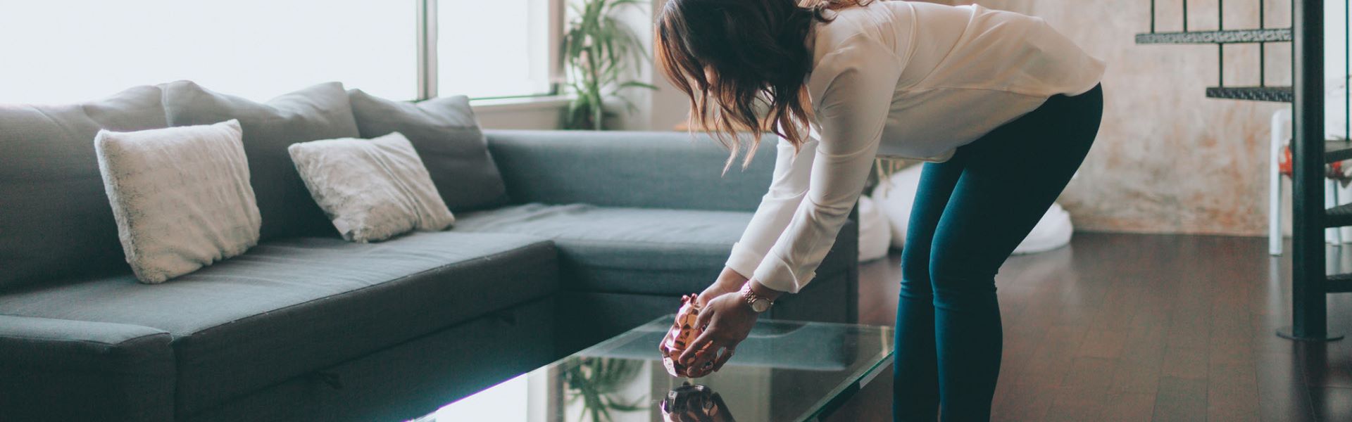 Une femme se penche pour poser une décoration dans un salon décoré pour un home staging à Albi.