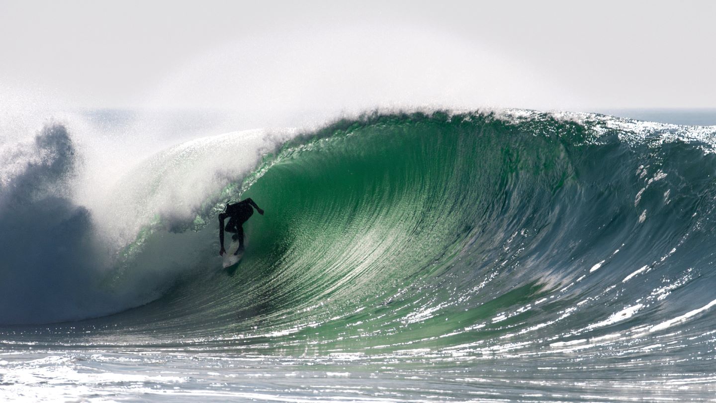 Un surfeur prenant une vague à Hossegor, destination idéale pour les passionnées de sports nautiques