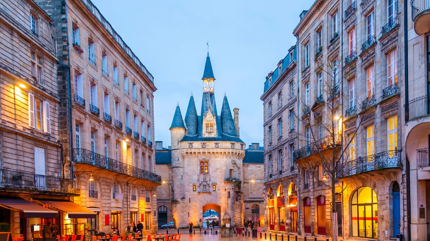 Une rue bordelaise, point de départ pour quitter la capitale et s'installer à Bordeaux, où un magnifique château se dresse en arrière-plan.